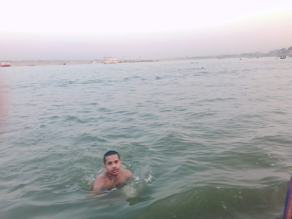ガンジス川で泳いでいる青年